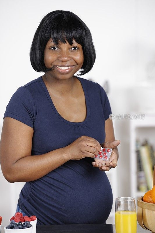 怀孕的非洲裔美国妇女持有药物/药丸/药片的肖像
